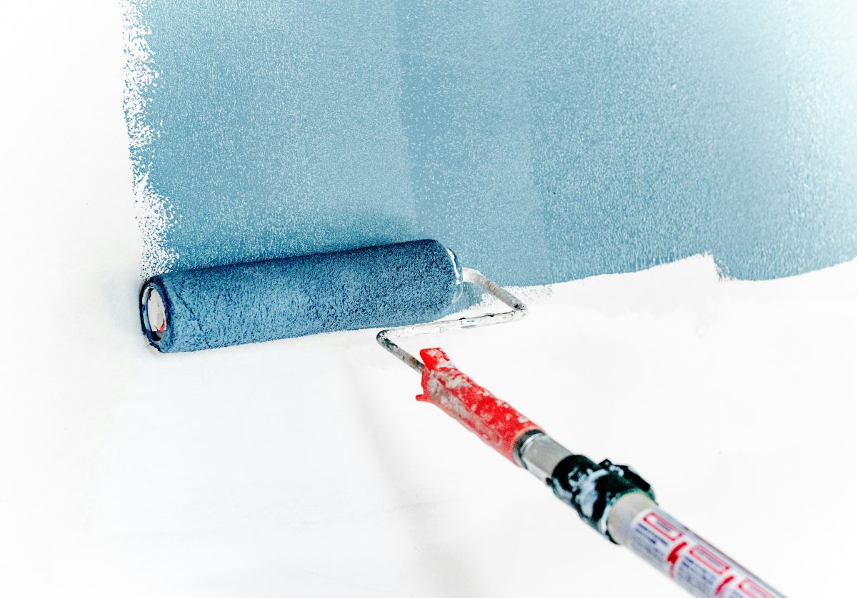 Verfroller die een muur blauw verft